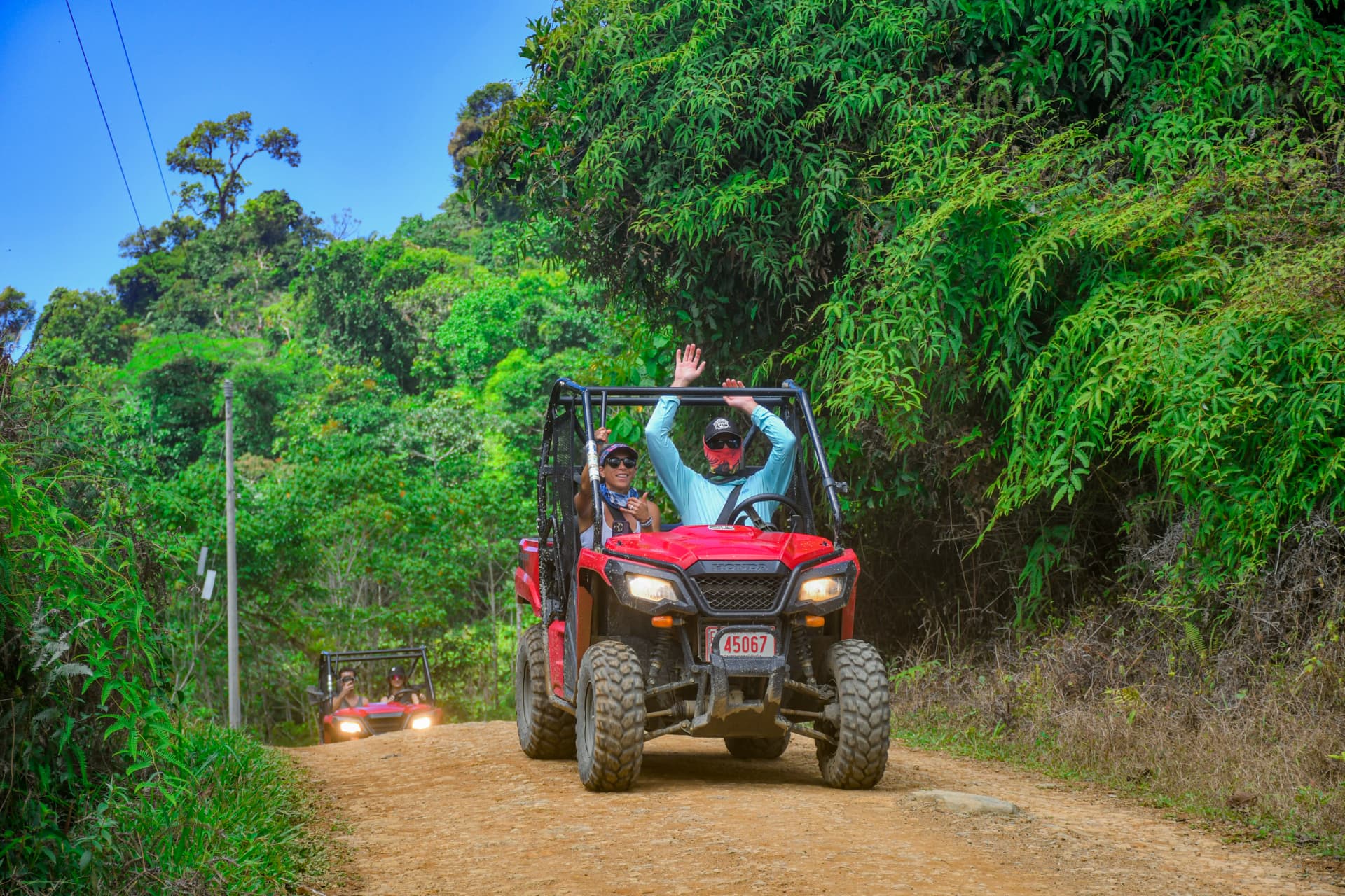 Guests waving from a side-by-side on a jungle road