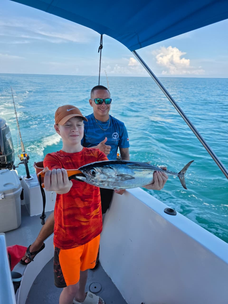 Young angler holding a tuna on the boat