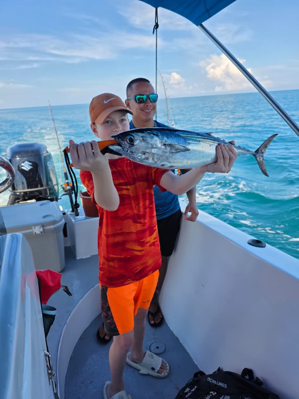 Young angler holding a tuna offshore
